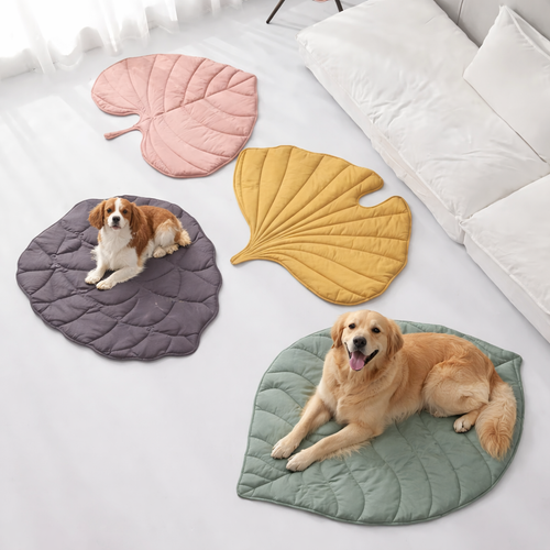 Leaf-shaped cooling mats for dogs in pink, yellow, green, and gray with large dogs resting on them indoors
